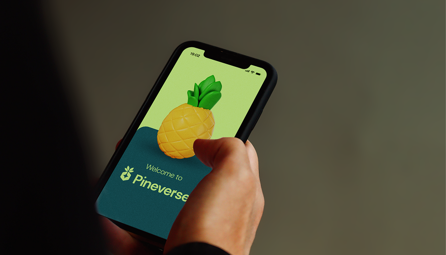 A hand holding a phone showing the Pineverse welcome screen
